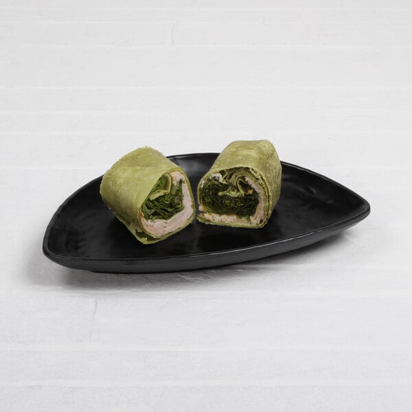 A black Elite Global Solutions half-moon tray with two wraps, one with meat and lettuce on it.