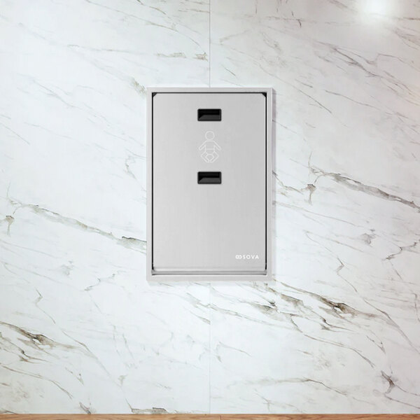 A recessed vertical stainless steel baby changing station mounted on a marble wall.
