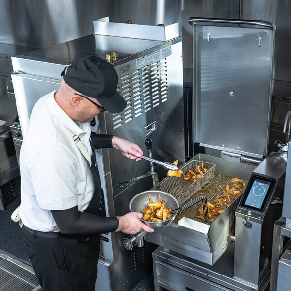 A commercial kitchen worker using a Cleveland SET-10 10 gallon electric countertop tilt skillet with easyTouch controls.
