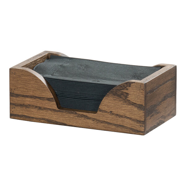 A rectangular oak wood napkin holder containing black napkins.
