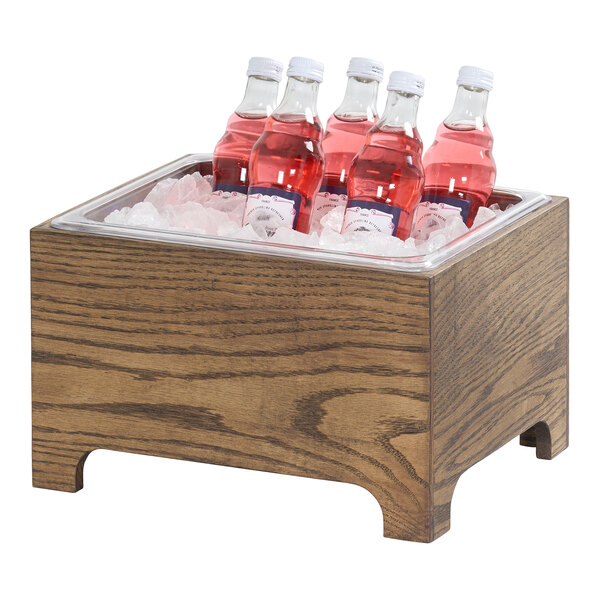 A wooden Cal-Mil Melrose 10x12 ice housing filled with ice and bottles of pink beverage.
