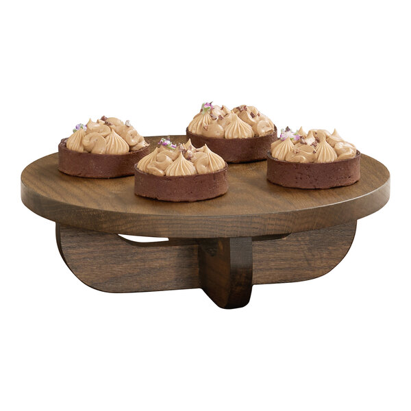 A round chocolate brown oak wood riser displaying four small desserts.