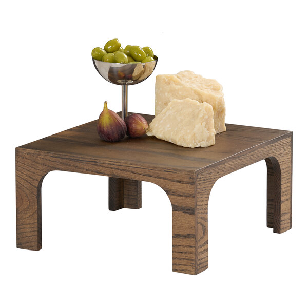 A square chocolate brown oak wood riser with food items displayed on top.