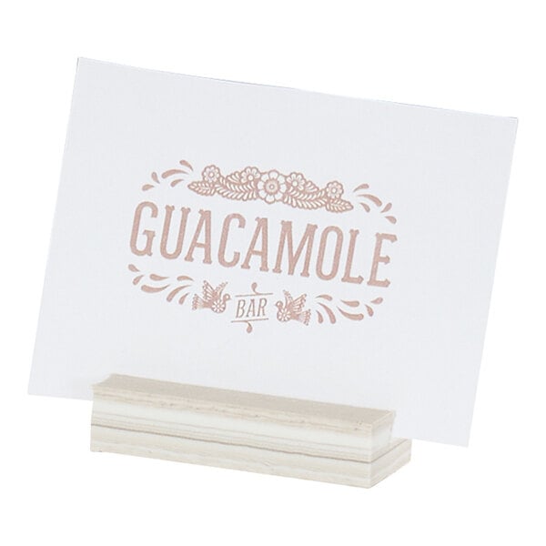 A white card holder with a wooden base displaying a card labeled 'Guacamole Bar.'