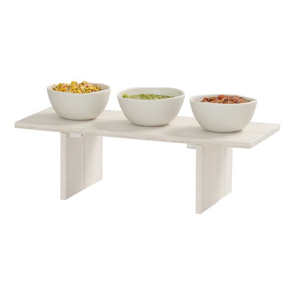 A rectangular coastal HDPE display riser with three white bowls containing different foods placed on top.