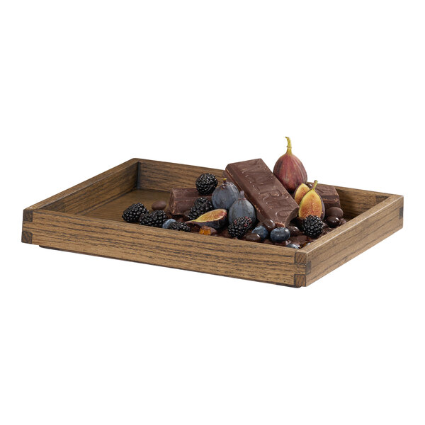 A rectangular oak wood tray with short sides, shown holding assorted fruits and chocolate.