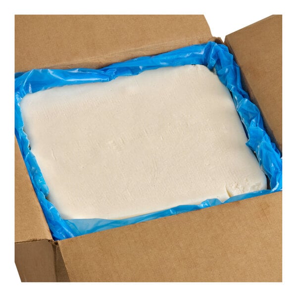 A large rectangular block of bacon fat in a cardboard box lined with a blue plastic bag.