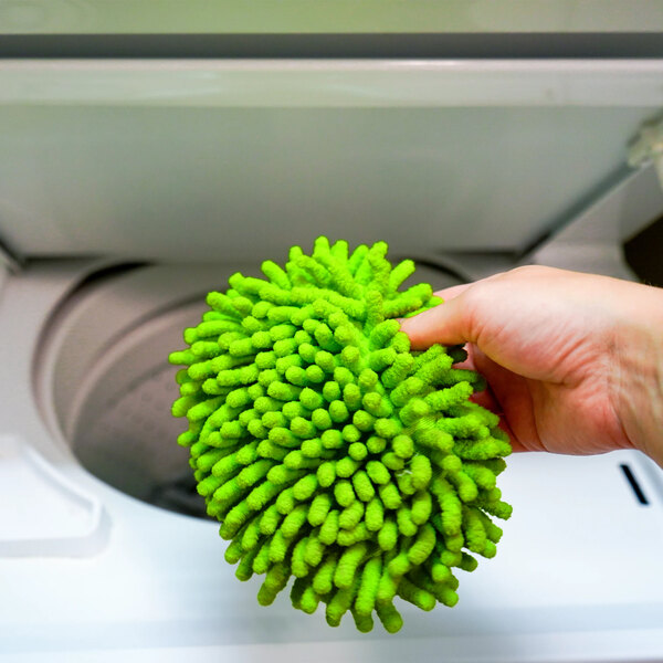 A green Libman 7 1/2" x 5" microfiber duster being held in front of a washing machine.