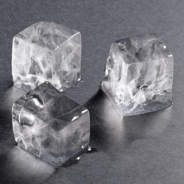 A set of three clear, square ice cubes on a dark surface.