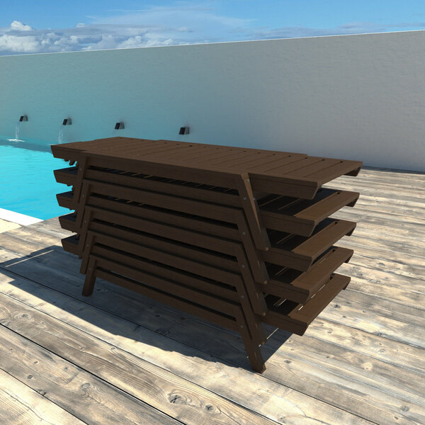 A stack of brown adjustable poly-lumber chaise lounges on a wooden deck by a pool.
