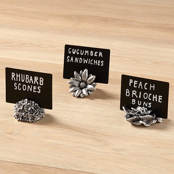 A set of whimsical polyresin daisy card holders used for displaying labels or cards.