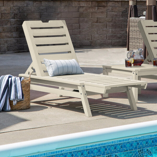 A white adjustable poly-lumber chaise lounge with a slatted design, positioned beside a pool.