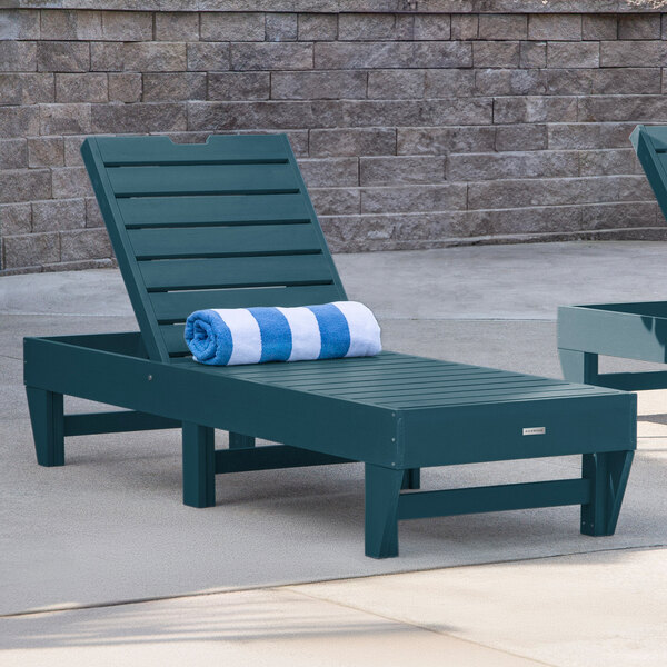 A blue adjustable poly-lumber chaise lounge with a rolled striped towel placed on it.