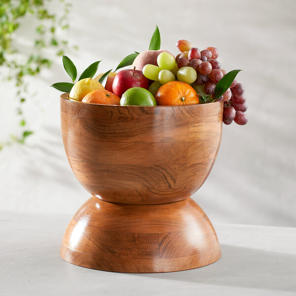 A round acacia wood hourglass bowl set filled with assorted fruits.