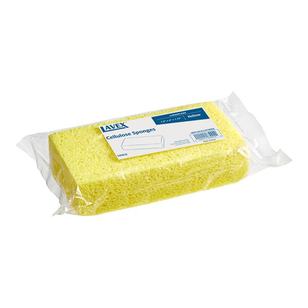 A rectangular yellow sponge is packaged in clear plastic with a label on top.