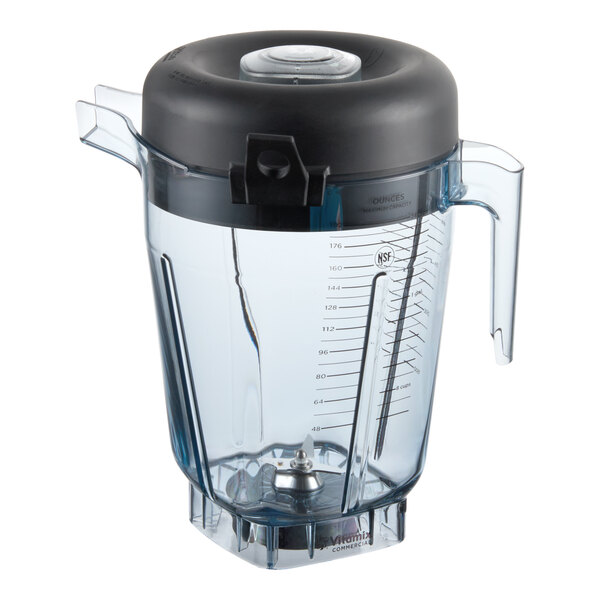 A large clear plastic blender container jar with measurement markings, a handle, a black lid, and a built-in blade assembly.