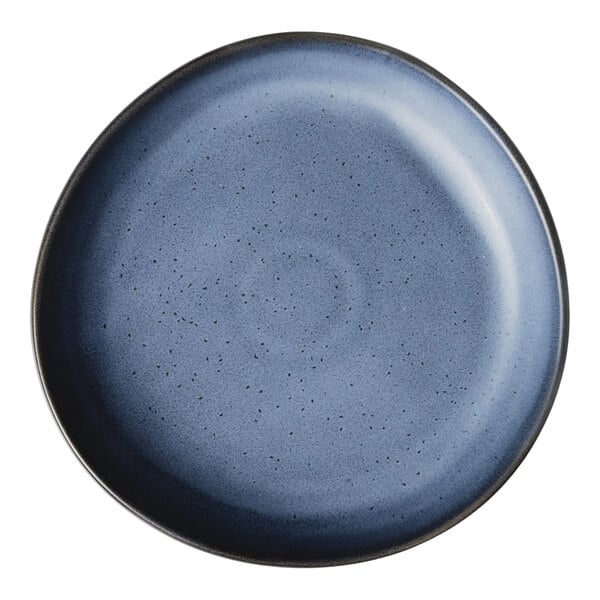 A round, matte blue porcelain plate with a subtle speckled pattern and a slightly raised rim.