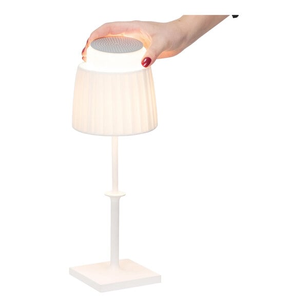 A white cordless rechargeable table lamp with a removable top, shown being lifted by a hand.