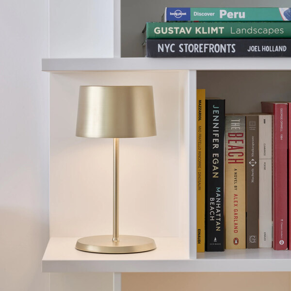 A small satin brass cordless rechargeable table lamp with a minimalist design.