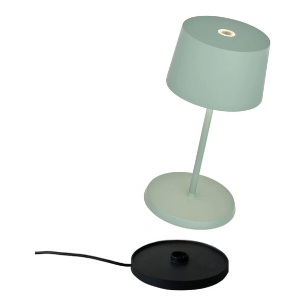 A small sage-colored cordless rechargeable table lamp with a matching base and a separate black charging pad.