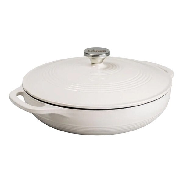 A white enameled cast iron casserole dish with a lid and side handles.