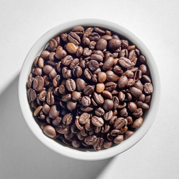A white bowl filled with whole coffee beans.