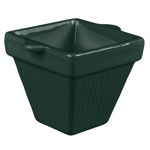 A hunter green square cast aluminum bowl with a handle.