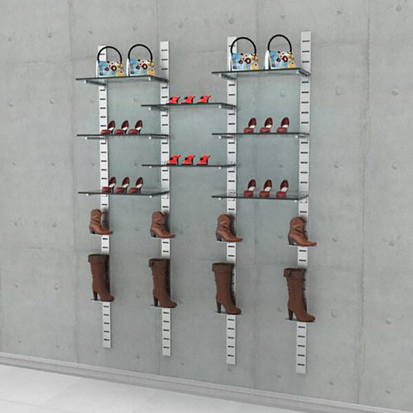A wall-mounted retail shoe display system with three vertical sections, glass shelves, and shoe displayers for showcasing footwear and handbags.