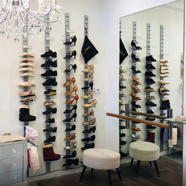 A vertical wall-mounted retail shoe display with multiple shelves holding various pairs of shoes.