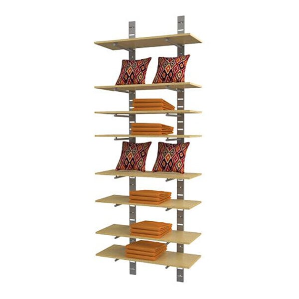 A vertical wall-mounted retail display unit with eight wooden shelves, holding folded orange fabric and patterned pillows.