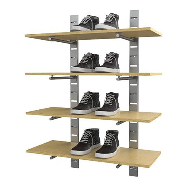 A vertical wall-mounted retail display with four wooden shelves holding pairs of shoes.