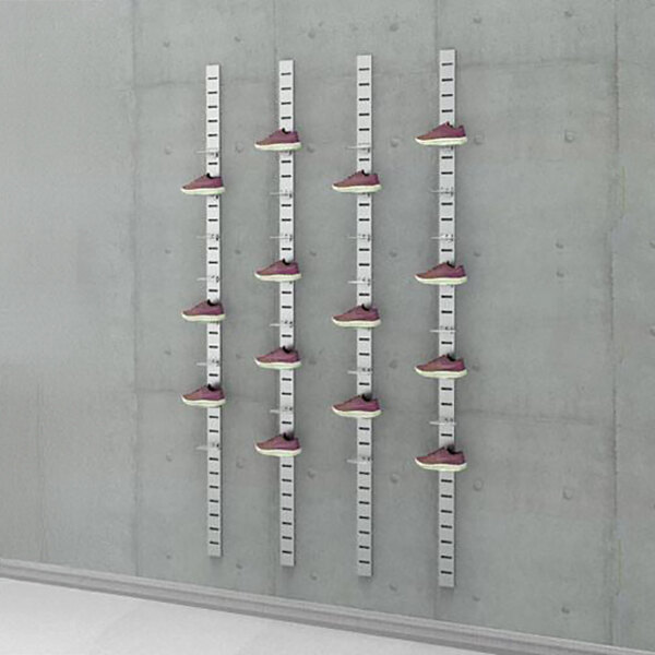 A vertical wall-mounted retail shoe display with four metal slat strips and multiple wire holders showcasing individual shoes.