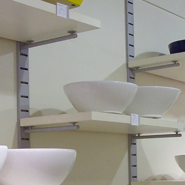 A vertical wall-mounted retail display with four wooden shelves holding various bowls.