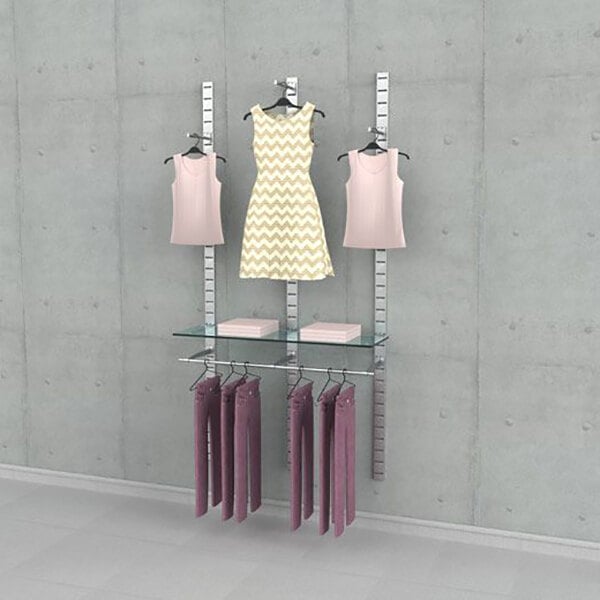 A vertical wall-mounted retail clothing display with metal slat strips, glass shelves, hanging rails, and faceouts showcasing various garments.