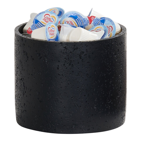 A black resin cylindrical riser filled with single-serve coffee creamer pods.