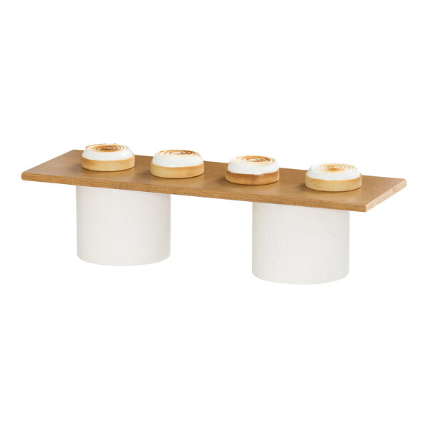 A rectangular rustic pine wood riser shelf with two white cylindrical supports.