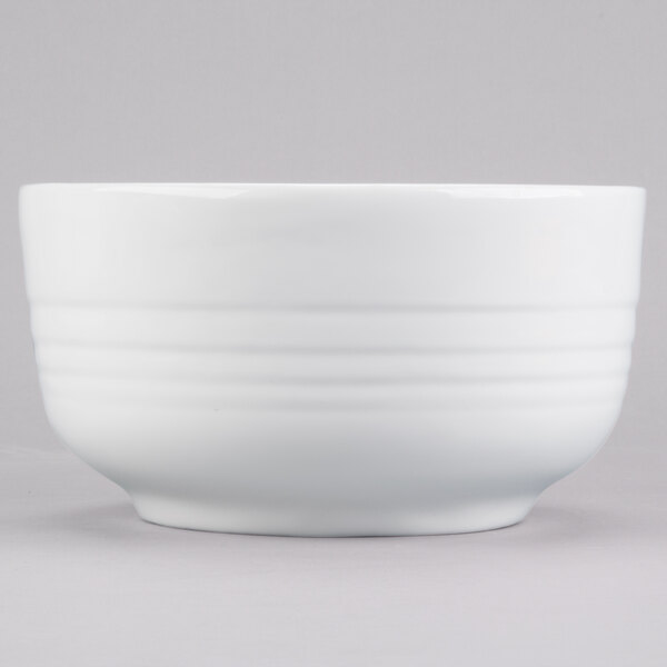 A white Tablecraft cast aluminum fruit bowl with a white rim.