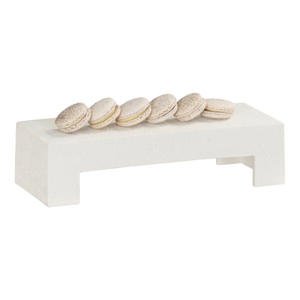 A rectangular ivory resin riser displaying six light-colored macarons.