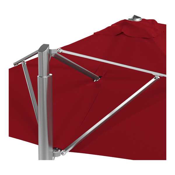 A square cantilever umbrella with a jockey red Sunbrella canopy and a silver aluminum base.