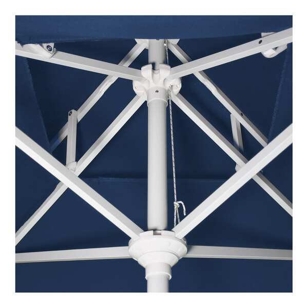 A close-up view of the internal frame and pole of a blue patio umbrella with a white aluminum structure.