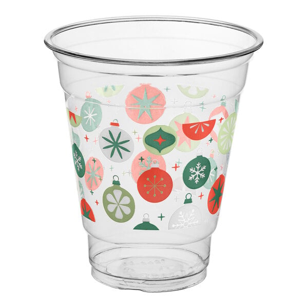 A clear plastic cup decorated with colorful holiday ornament designs in red, green, and white.