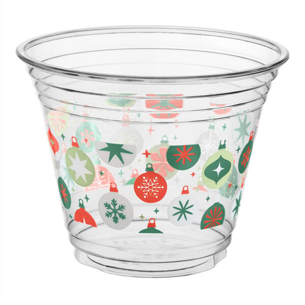 A clear plastic cup decorated with colorful holiday ornament designs in red, green, and white.