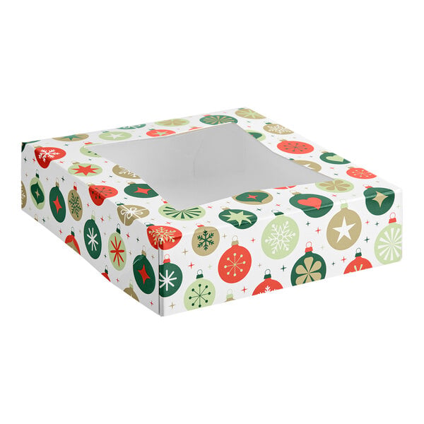 A square bakery box with a clear window on top, decorated with a festive ornament pattern in red, green, and gold colors.