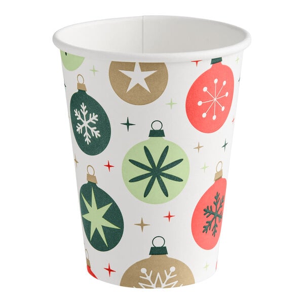 A paper cup decorated with colorful Christmas ornament designs in green, red, and gold tones.