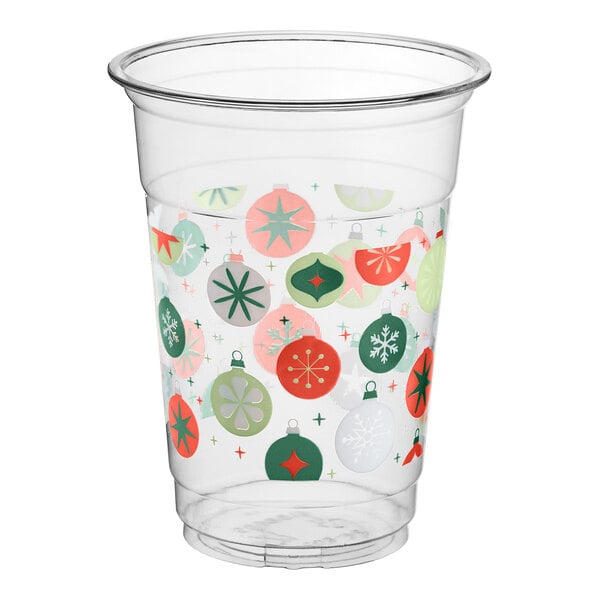 A clear plastic cup decorated with colorful Christmas ornament designs in red, green, and white.