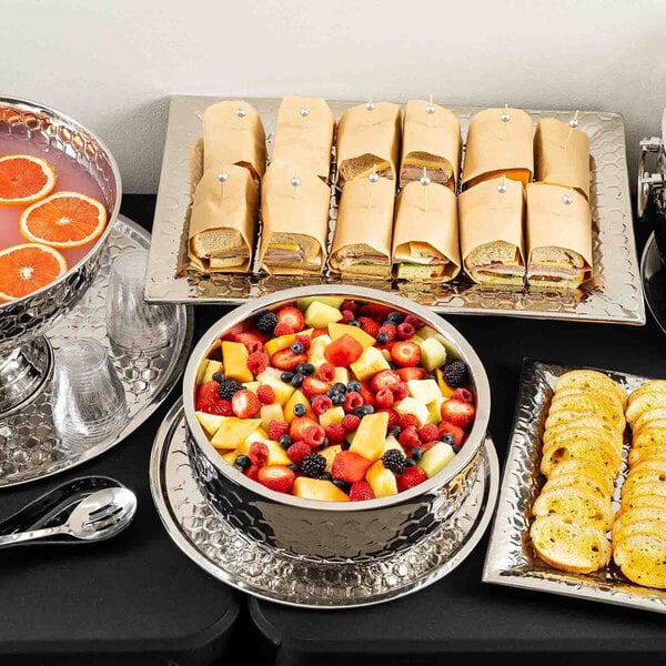 A large rectangular stainless steel serving tray with a honeycomb pattern, displayed with wrapped sandwiches.
