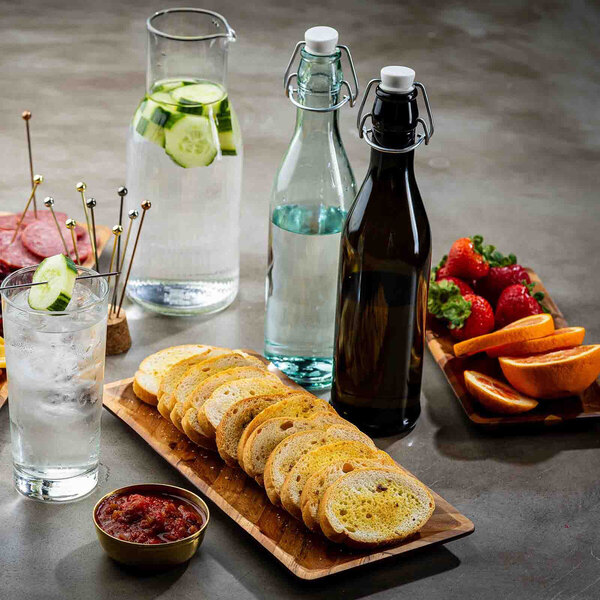 A dark green glass cruet with a stopper, shown alongside other food and drink items on a table.