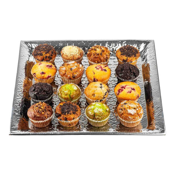 A large square stainless steel serving tray with a honeycomb pattern, holding an assortment of muffins.