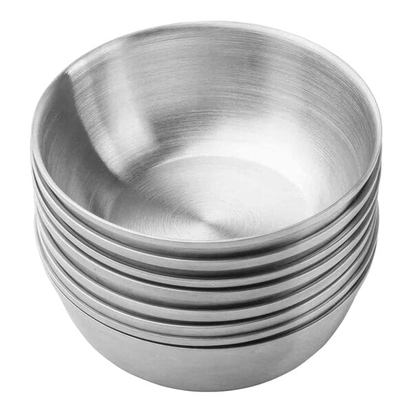 A stack of round stainless steel sauce cups.
