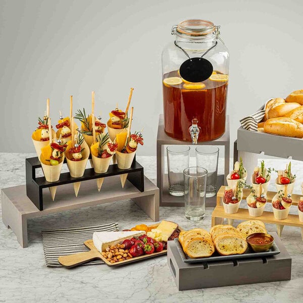 A three-piece set of rectangular gray wood risers used for displaying food and beverages.